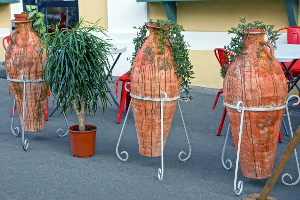 三个棕色花瓶，上面有绿色植物，是古老的陶土花瓶图片下载