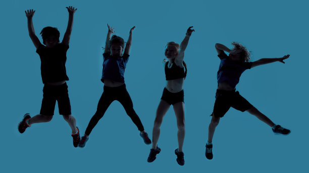 四个孩子的剪影全长拍摄，看起来快乐的摆姿势，跳跃孤立的蓝色背景图片下载