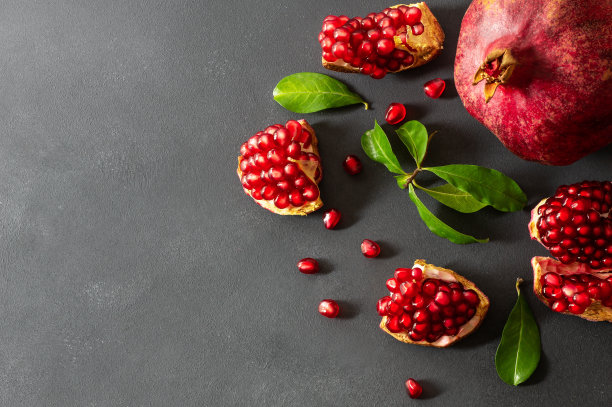 新鲜成熟的整体和分裂多汁的石榴，种子和叶子在木制的乡村背景，健康的红色水果概念复制空间(石榴)图片下载