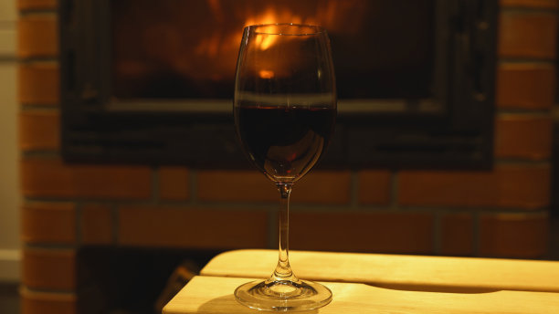 壁炉边放着一杯红酒。图片下载