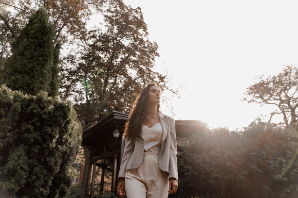 在绿色的公园里的微笑女孩。快乐的年轻女子绕着绿色的花园散步。年轻女商人的生活方式。图片下载