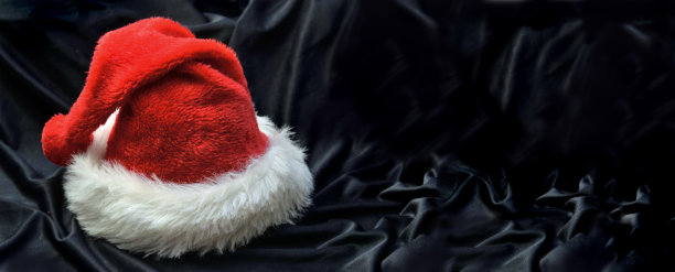红色的圣诞老人帽在黑色的纺织背景图片下载
