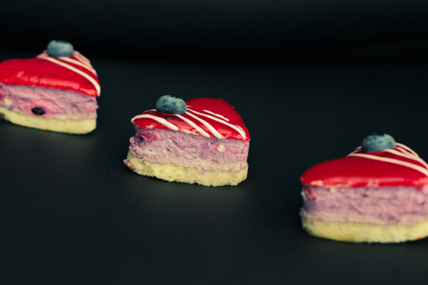 三个心形的小蛋糕，在选择焦点的黑暗背景上被太阳光线照亮图片下载