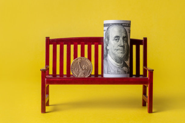 1枚美元硬币和一张卷起的100美元钞票图片下载