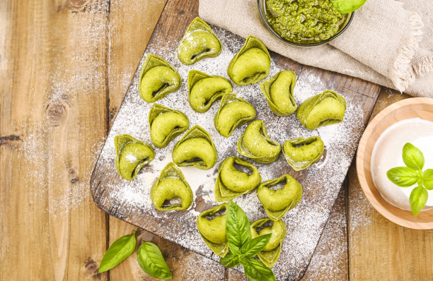 意大利饺子是典型的意大利饺子。食物背景自制生意大利饺子和绿色香蒜沙司的原料在木制的背景。高角度的观点。副本的空间。图片下载