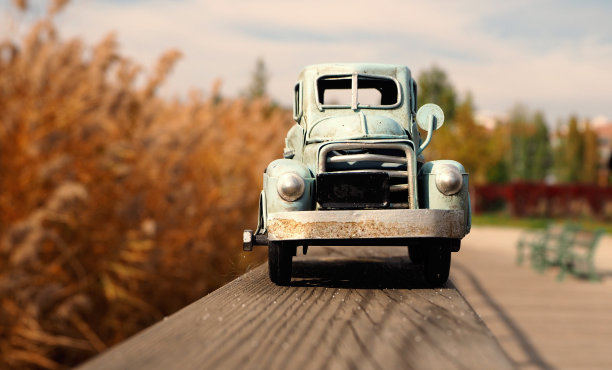 一辆老式玩具车停在树栏杆上。芦苇的背景图片下载