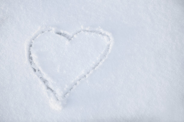 雪中的一颗心。一个心形画在雪地特写。雪地上的心形。冬天的背景。图片下载