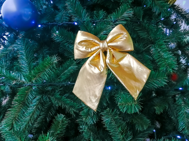 圣诞圣诞树上的金色蝴蝶结装饰，特写，柔和的焦点图片下载