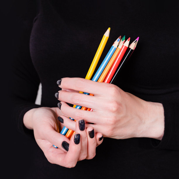 女性手拿彩色铅笔在黑色的背景。用黑色指甲油修指甲，复制空间图片下载