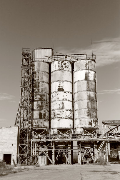 旧的，废弃的混凝土工厂有生锈的铁罐和金属结构。危机爆发，经济下滑，生产能力停止导致崩溃。全球灾难。老照片的效果图片下载