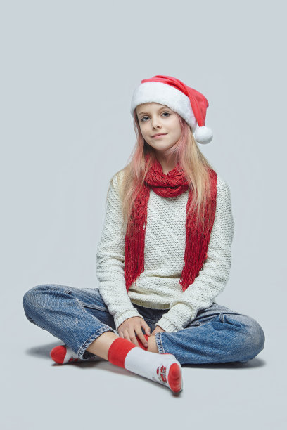 小女孩戴着圣诞老人的帽子。在工作室里以白色背景拍照图片下载