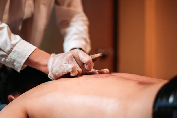 亚洲华人男性病人在中药店接受刮痧治疗图片下载