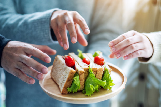 人们抓一块全麦三明治放在木盘子里吃图片下载