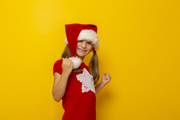 戴着圣诞老人帽子的孩子握着她的拳头在快乐中握紧图片下载