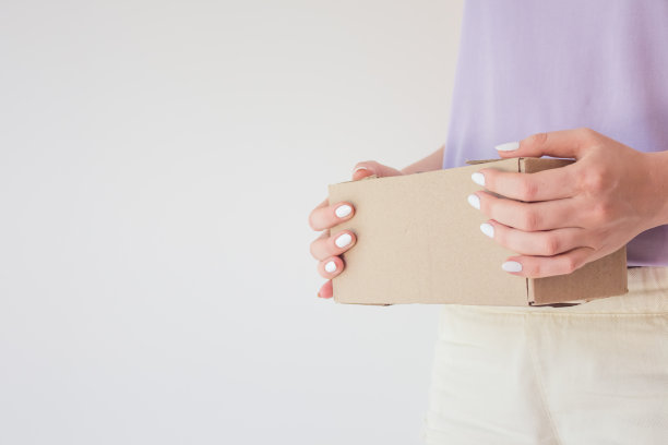 Сourier将包裹递送给收件人。满意的收件人手里拿着包裹的硬纸盒。交货时间的概念，快速交货图片下载