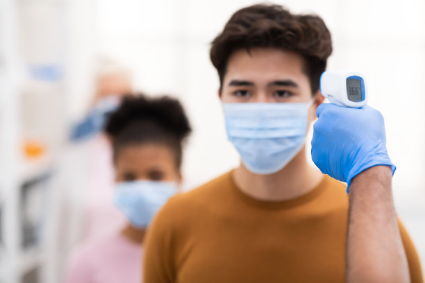 医护人员在室内对亚洲男性进行温度检测图片下载