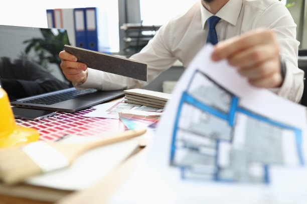 男人在桌子上持有一个公寓项目和样品整理材料。图片下载