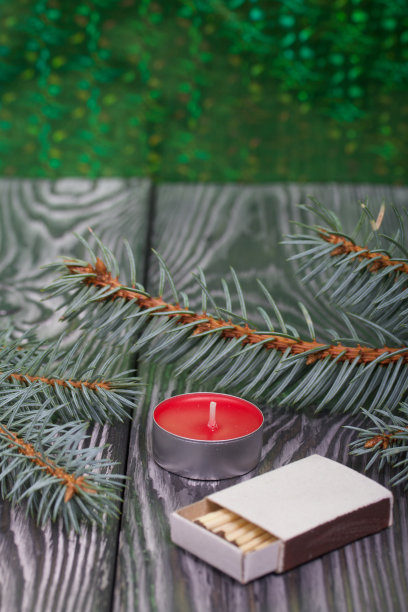 刷过的松板上的蓝色云杉树枝。旁边是一根蜡烛和一盒火柴。图片下载