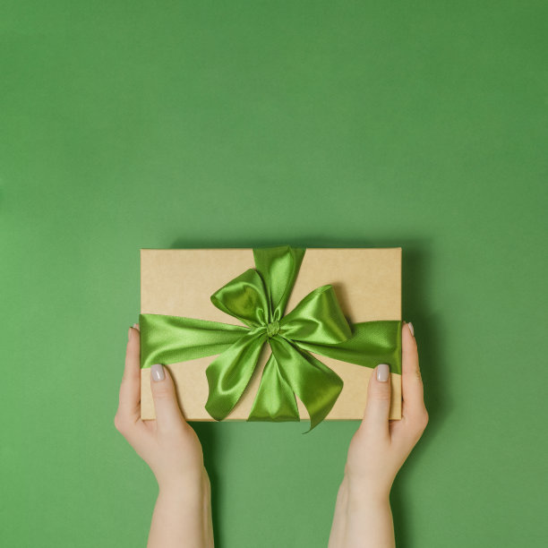 绿色桌子上拿着礼物盒的女人图片下载