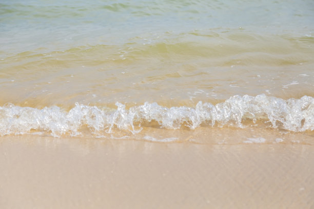 海浪的泡沫和沙滩上的沙子。海风把海浪吹到沙滩上。这张照片给人一种清新多汁的感觉。可用于添加文本和抽象背景。图片下载