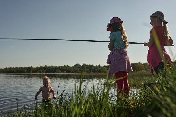 孩子们在一个大湖的岸边钓鱼。图片下载