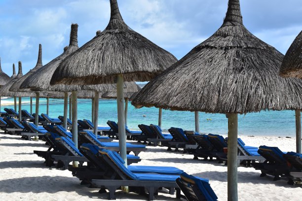 彩色的日光浴床排列在白色的沙滩上，面对着蓝色的海洋。海滩度假胜地。图片下载