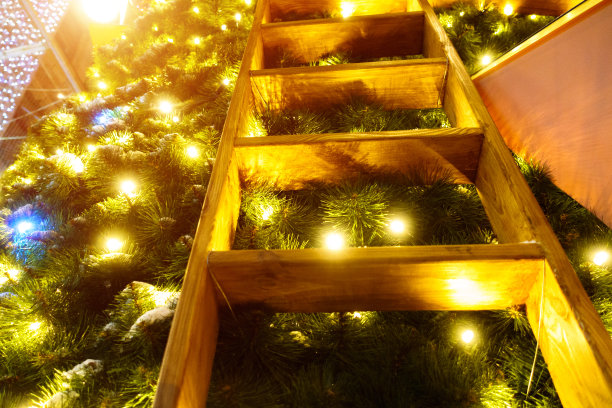 圣诞节的背景。圣诞树上明亮的灯光之间的木制楼梯图片下载