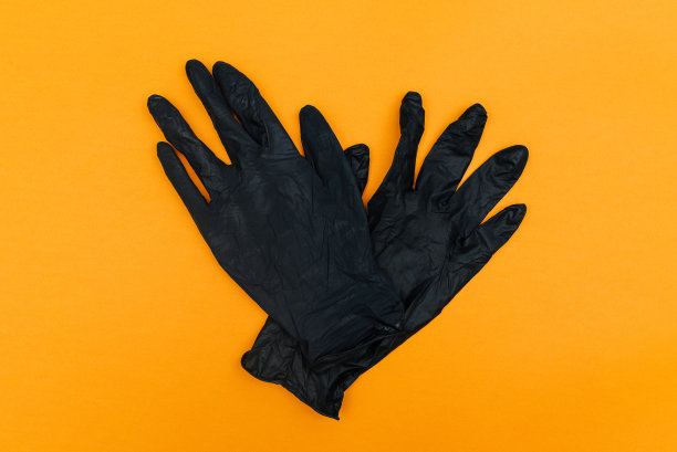 黑色一次性手套孤立在橙色背景上。手保护，防止冠状病毒感染，卫生。俯视图，平放图片下载