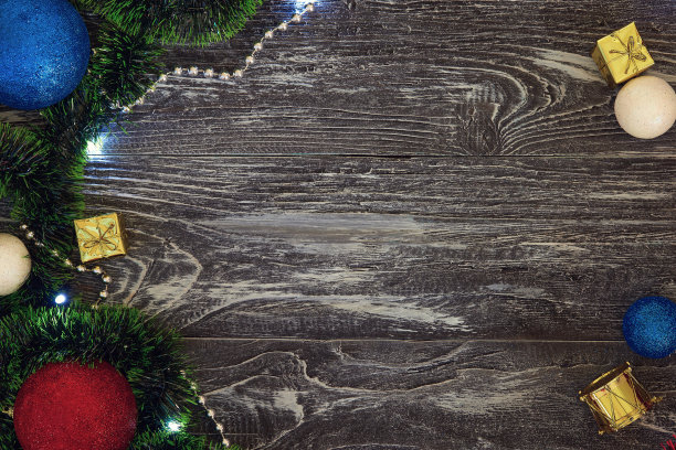 圣诞相框在左边，玩具在右边。平的。新年贺卡礼物。球，礼物，雪球，绿色和红色的金属箔。在灰色的木制背景上。带有文本拷贝空间的俯视图图片下载