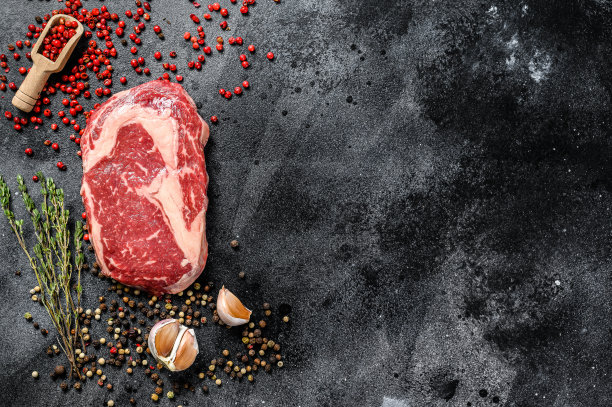 生鲜肉肋眼牛排配调味料。肋眼牛排。黑色背景。前视图。本空间图片下载