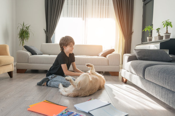 男孩们在做作业的时候和她的狗在地板上玩。图片下载