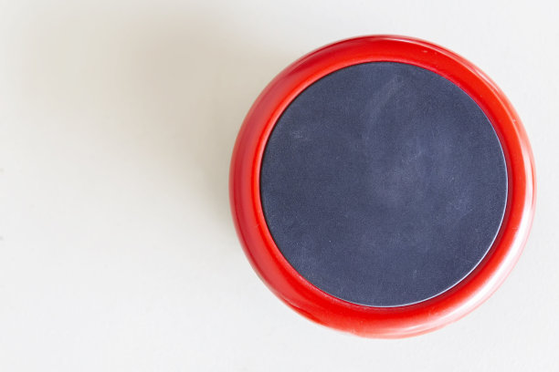 前视图的消防警铃的建筑上的白色墙壁。里面有黑点的红色圆圈，由金属制成。图片下载