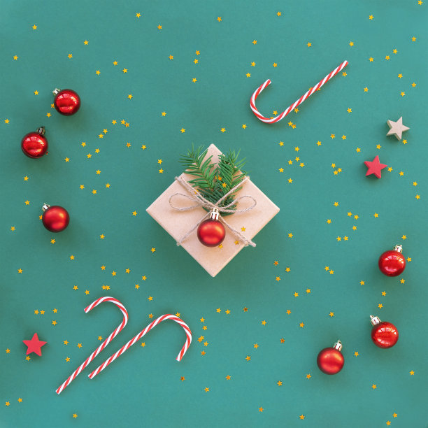 圣诞礼物装在盒子里，绿色背景上有五彩纸屑和红球。新年的概念。俯视图，平放图片下载