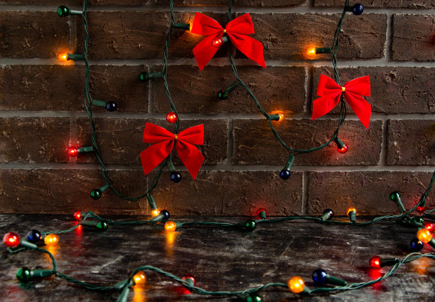 圣诞背景用红色的蝴蝶结和五颜六色的灯在棕色的砖墙上，大气和美丽的地方，为对象图片下载