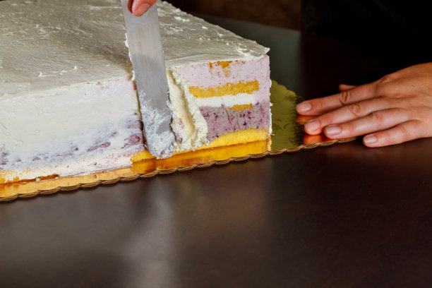 女人用糖霜覆盖节日蛋糕。制作多层海绵蛋糕。图片下载