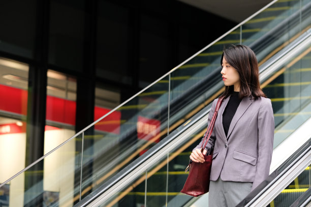 亚洲年轻女子乘自动扶梯下楼图片下载