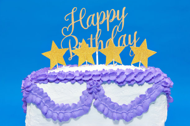 用星星形状和黄色的“生日快乐”字样装饰的自制生日蛋糕。在蓝色背景下隔离图片下载