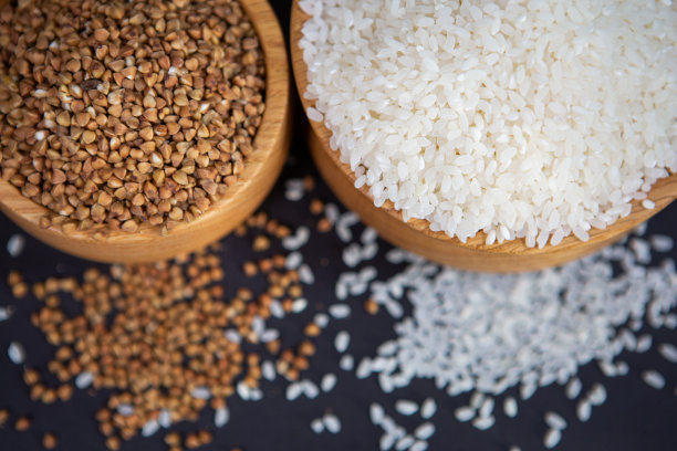 特写照片的荞麦和大米，生在一个时尚的木碗在黑暗的背景。图片下载