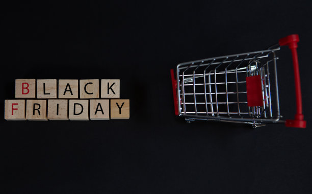 黑色星期五的概念在商店销售，立方体与黑色的单词和超市购物车在黑色的背景图片下载