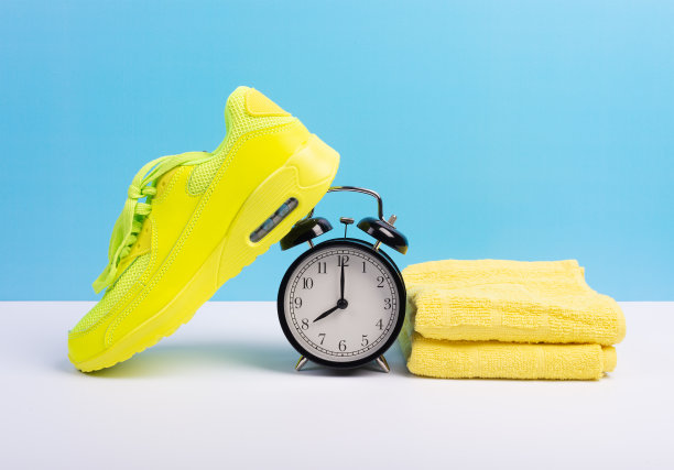 马拉松跑步的概念与运动鞋，毛巾和闹钟在蓝色墙的背景图片下载