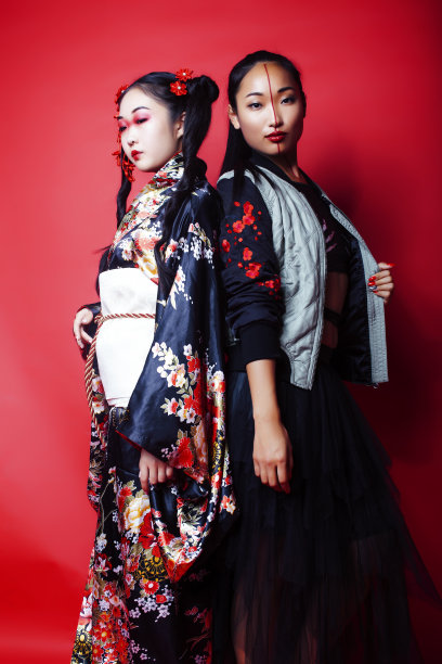 两个漂亮的艺妓朋友:现代亚洲女性和传统穿着和服摆出欢快的红色背景图片下载