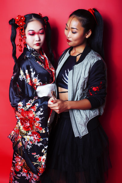 两个漂亮的艺妓朋友:现代亚洲女性和传统穿着和服摆出欢快的红色背景图片下载