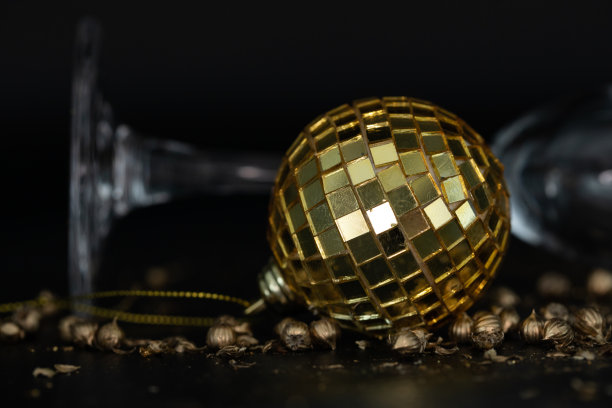 金色的圣诞球和金色闪闪的黑色背景。新年图案。圣诞节的背景。金色的圣诞装饰品和酒杯。节日的背景图片下载