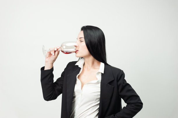 一个穿着黑西装拿着一杯酒的女人的肖像图片下载