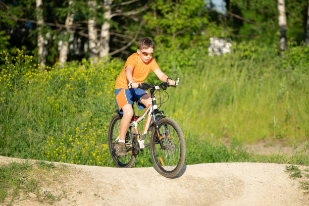 男孩戴着太阳镜骑着自行车在崎岖的道路上图片下载