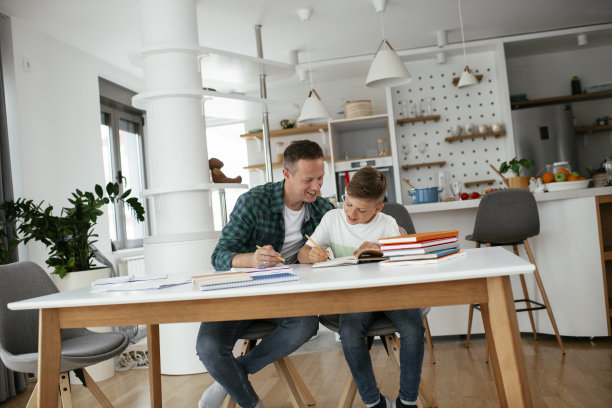父亲在家里帮助儿子做作业。图片下载