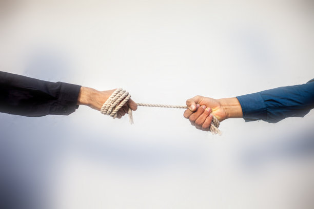 近距离拍摄的两名男性手玩拔河的背景模糊。图片下载