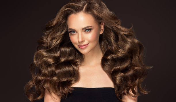 年轻，棕色头发美丽的模型，长，卷曲，整齐的头发。优秀的头发。美发艺术与护发。图片下载