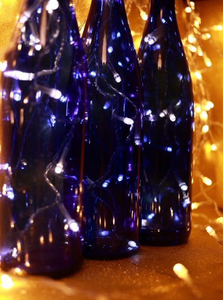 蓝色玻璃瓶的静物与圣诞发光的花环内在一个金色的背景。图片下载