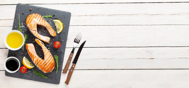 木桌上放着烤鲑鱼、沙拉和调味品图片下载